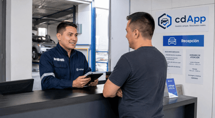 Recepcionista de CDA uniformado con overol azul recibiendo a un cliente y registrando datos en una tableta digital